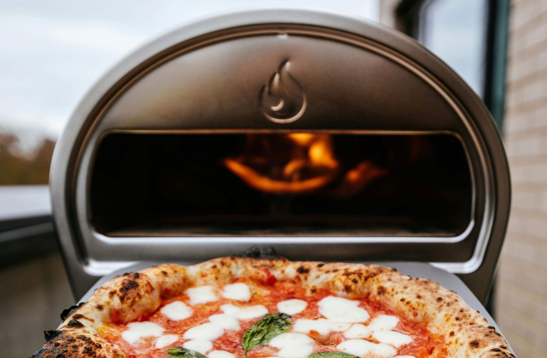 Best Home Pizza Oven Blog Post Image close up of Gozney Roccbox oven with cooked pizza being removed
