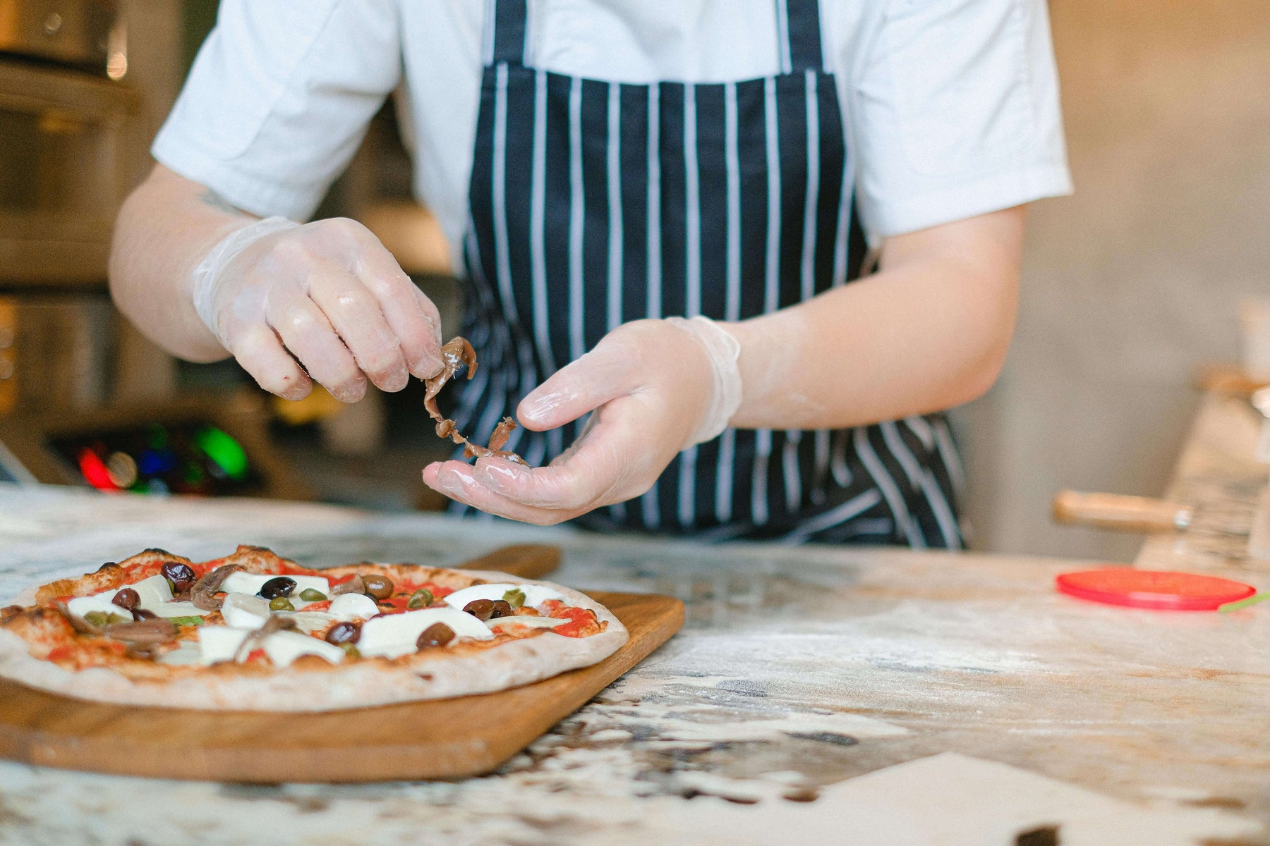 person preparing pizza on wood pizza peel for article: best wooden pizza peel