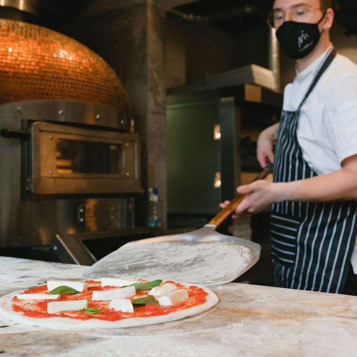 Person cooking with metal pizza peel