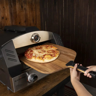 Blackstone wood pizza peel removing pizza from Blackstone pizza oven